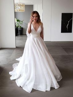 a woman in a white wedding dress posing for the camera with her hand on her face