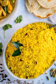 a bowl filled with yellow rice next to pita bread