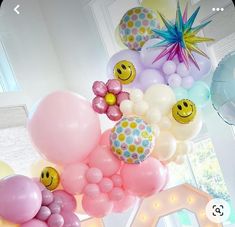 a bunch of balloons with smiley faces on them hanging from the ceiling in a room