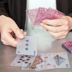 a man is playing with some cards on the table and one has pink beads in his hands