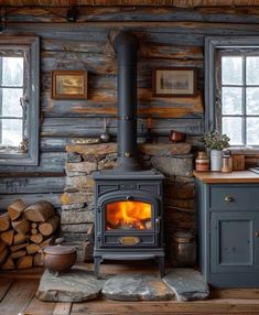 a wood burning stove in a log cabin with logs stacked on the floor next to it