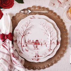 a white plate with red designs on it next to silverware and flowers in vases