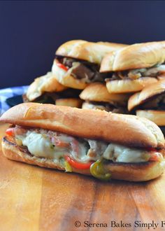 two sub sandwiches sitting next to each other on a wooden table with blue and white checkered napkins