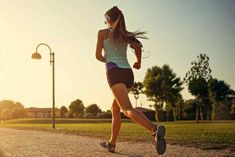 a woman is running on the road with her headphones in her ears and wearing shorts