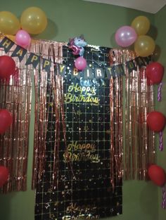 a birthday party with balloons and streamers on the wall in front of a curtain