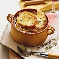 a pot filled with food sitting on top of a table next to a glass of wine