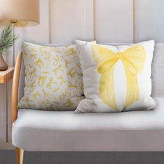 two yellow and white pillows sitting on top of a couch