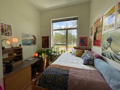 a bed room with a neatly made bed and lots of pictures on the wall above it