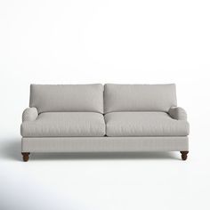 a white couch sitting on top of a wooden floor next to a wall with a light colored background