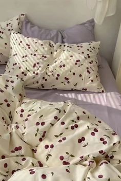 an unmade bed with cherry print sheets and pillows