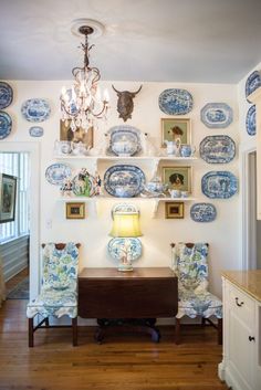 blue and white plates hang on the wall above a table with two chairs in front of it