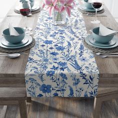 the table is set with blue and white plates, napkins, and flowers in a vase