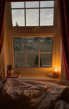 a bedroom with a bed and a window that is lit up by candles on the windowsill