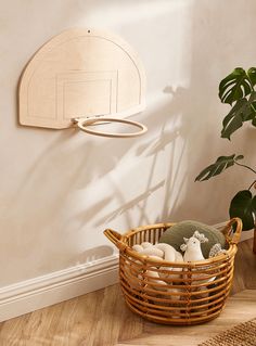 a basket on the floor next to a potted plant and a wall mounted shelf