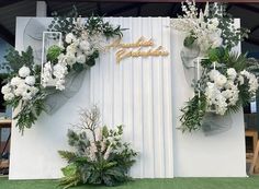 an outdoor event with flowers and greenery on the wall, in front of a sign that says paradise garden