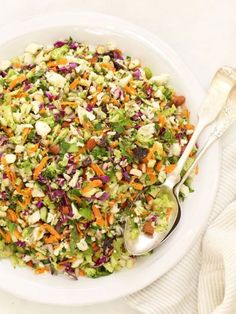 a salad with carrots, celery, and other vegetables in a white bowl