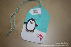 a penguin tag that says let it snow on the front, and is attached to a string