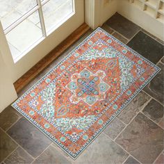 an orange and blue rug is on the floor in front of a door with windows