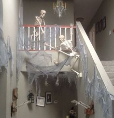 a hallway decorated for halloween with skeletons and spider webs on the railing, hanging from the ceiling