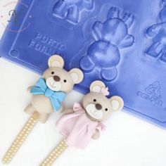 two teddy bears sitting next to each other on top of a white table with blue molds