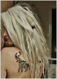 a woman with long white hair has a tattoo on her upper arm and behind her back