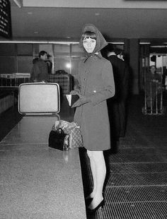 a woman standing in an airport with her hand on her hip and luggage behind her