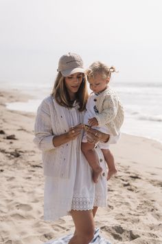 a woman holding a baby on the beach