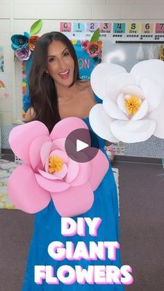 a woman in a blue dress holding giant paper flowers with the words diy giant flowers