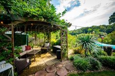 a covered patio area with seating and trees in the background, surrounded by greenery