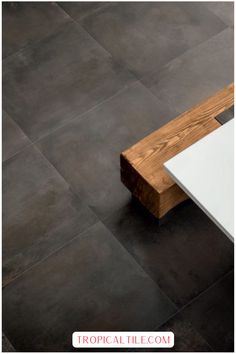 a wooden bench sitting on top of a tiled floor next to a white table and chair