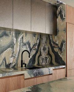 a kitchen with marble counter tops and wooden cabinets, along with a black faucet