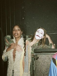 two women dressed in costumes posing for the camera with their faces painted like clowns