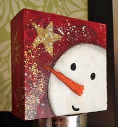 a snowman painted on a red block with gold stars