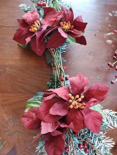 two poinsettis are sitting on the floor next to some pine needles and berries