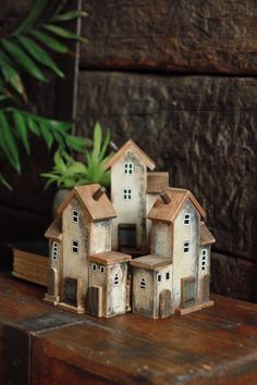 a group of small houses sitting on top of a wooden table next to a potted plant