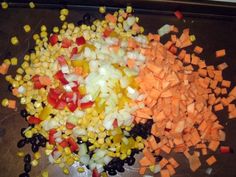 chopped up vegetables on a cutting board with some black olives, corn and carrots