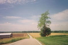 an empty country road with a barn in the distance