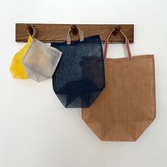 three bags are hanging on a wooden hook