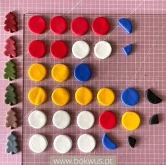 several different shapes and sizes of buttons on a piece of pink paper next to each other