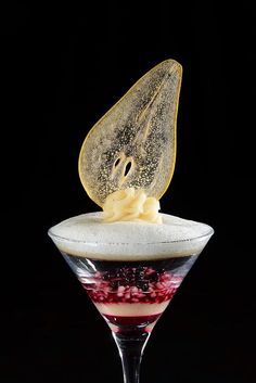 a dessert in a martini glass topped with whipped cream and berries