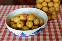 a bowl filled with green apples sitting on top of a red and white checkered table cloth