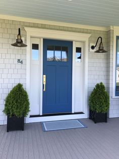 a blue front door with two black planters