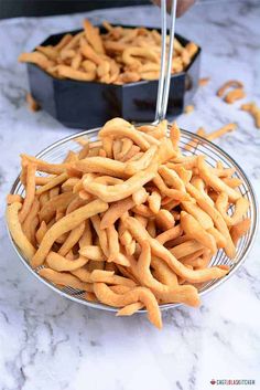 there is a bowl full of churros on the counter next to two pans