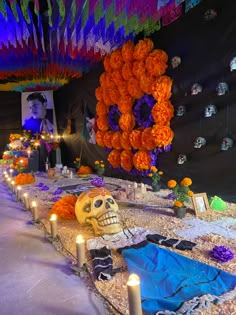 a long table with candles and skulls on it, decorated with orange flowers and decorations