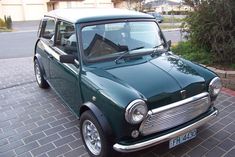 an old green car is parked on the side of the road