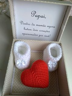 a box with two knitted baby booties in the shape of a heart inside