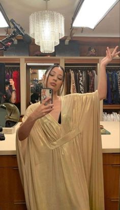 a woman is taking a selfie with her cell phone in a clothing store,