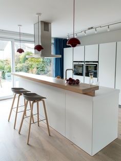 a kitchen with two bar stools next to an island in front of a window