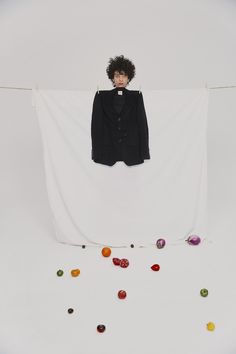 a man standing in front of a white backdrop with balls hanging from the clothes line