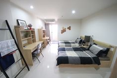 two beds in a room with white walls and flooring next to a book shelf